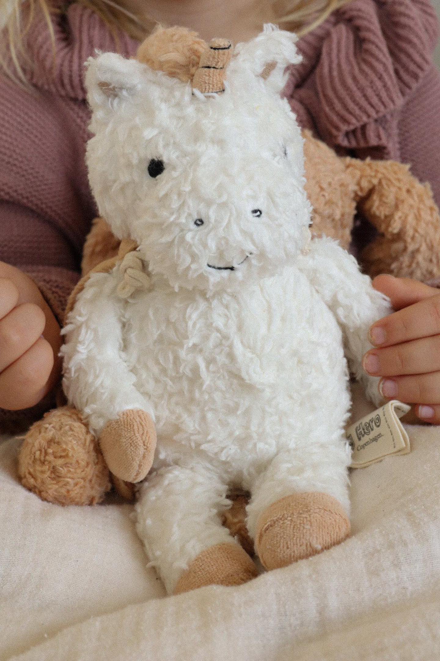 Enhjørning fra Sleeping Hero. Denne bamse måler 26 cm og er den perfekte størrelse til dit barn at putte med og tage med på farten. Arme og ben er lavet ekstra lange, så de er nemme at gribe om for selv små hænder. Maven er fyldt med natursten, der har en beroligende vægt, når helten putter med sin ejer. Den kommer med en aftagelig kappe, der både fungerer som nusseklud og sutteholder. Og med sin holdbare konstruktion holder den til mange års eventyr og legetid.